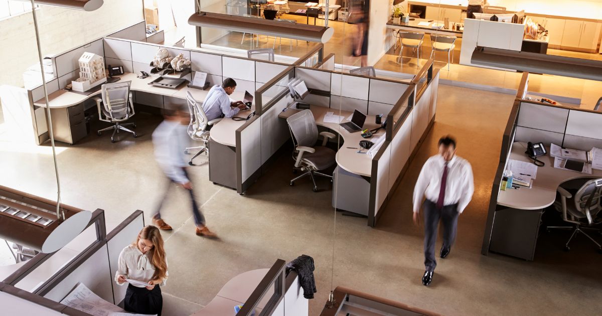 Office setting with cubicles and employees working and walking around